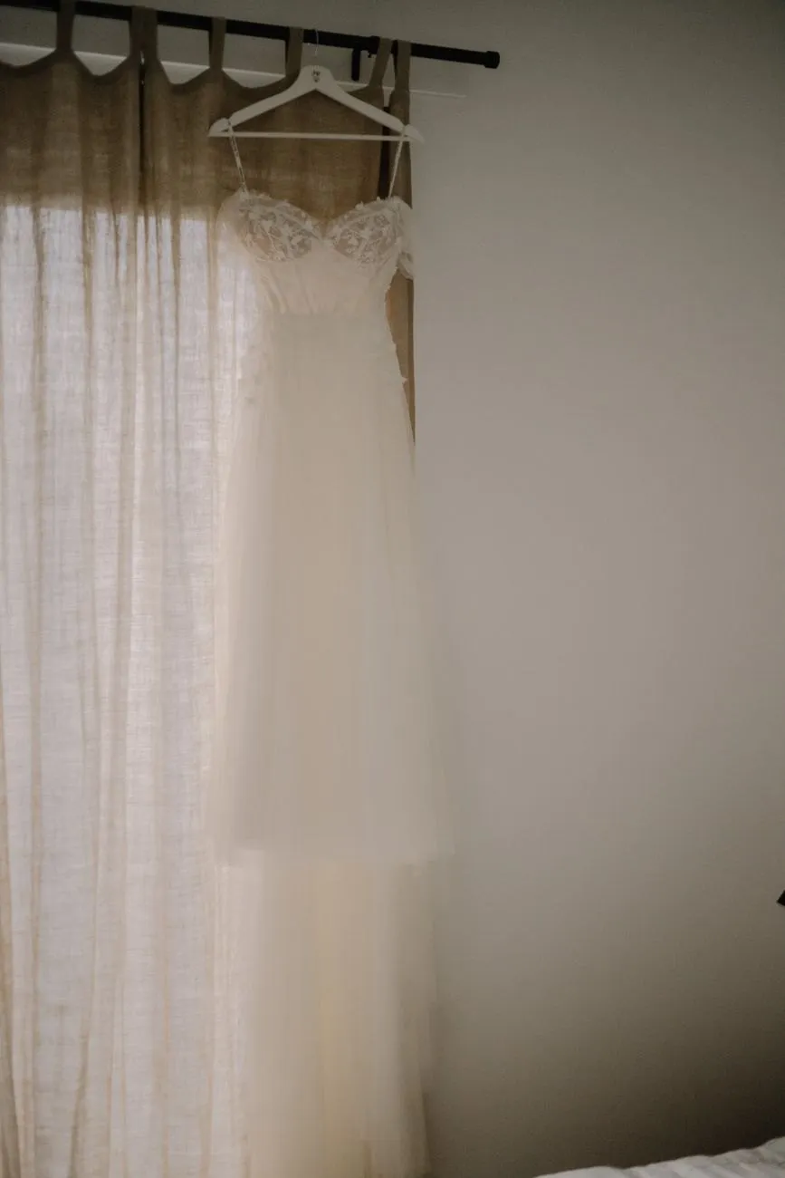 A wedding dress hanging behind a linen curtain