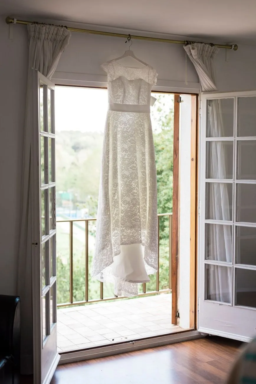 A lace wedding dress hanging in an open balcony doorway