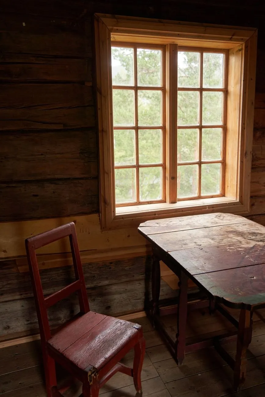 A paned window in a timber room above an old table