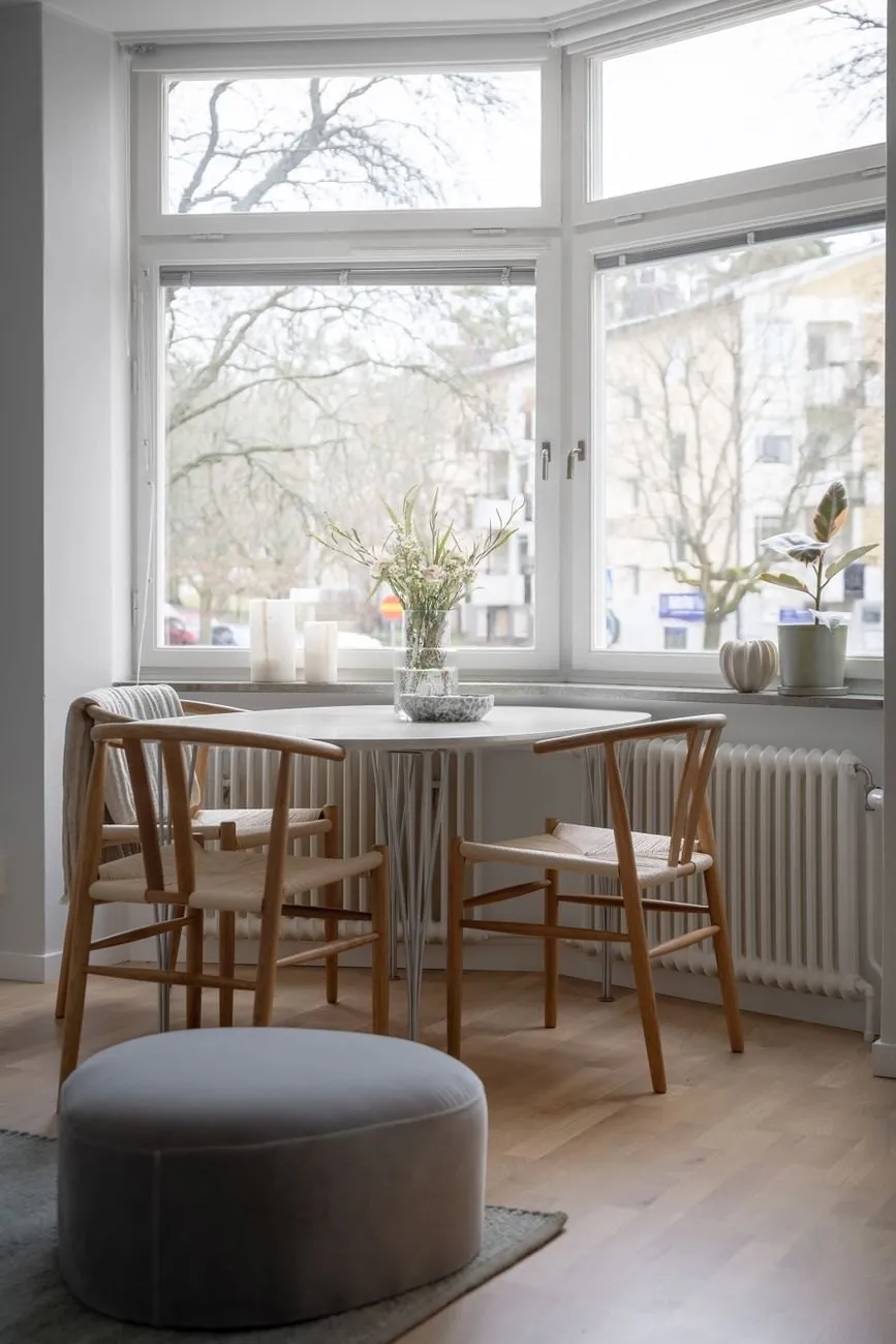 A bay window with a small round table and wooden chairs
