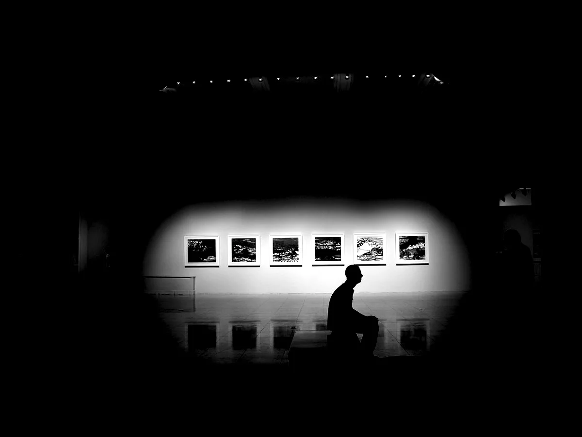 A darkened room with a line of lit prints along one wall.