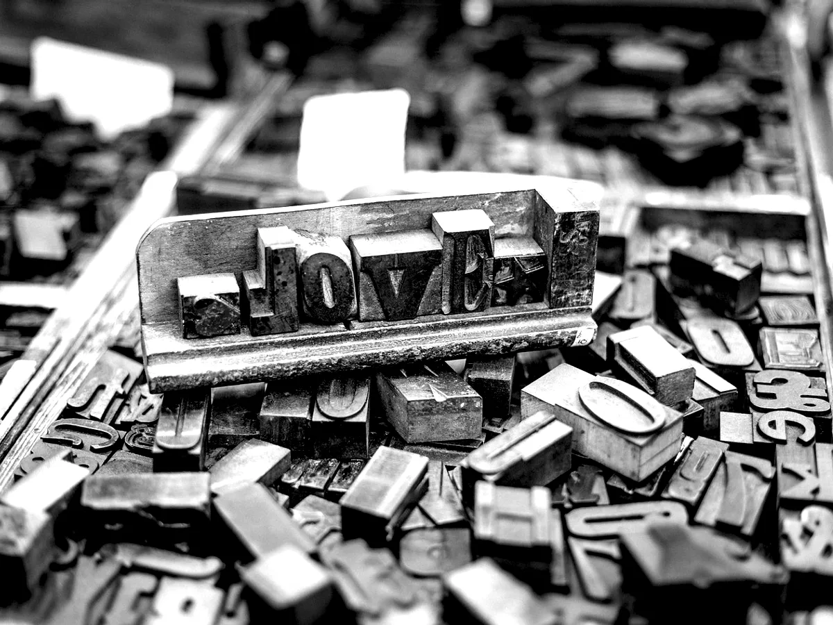 Loose metal type spilled across a bench beside a composing stick.